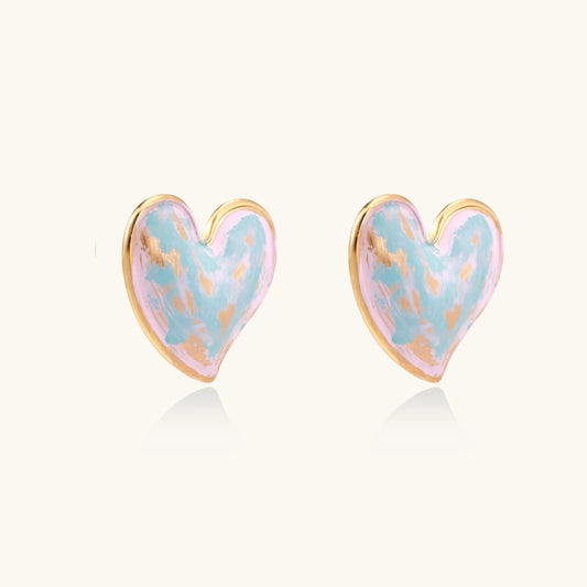 Heart-shaped stud earrings with swirled turquoise and pink enamel in gold-plated frames on cream background
